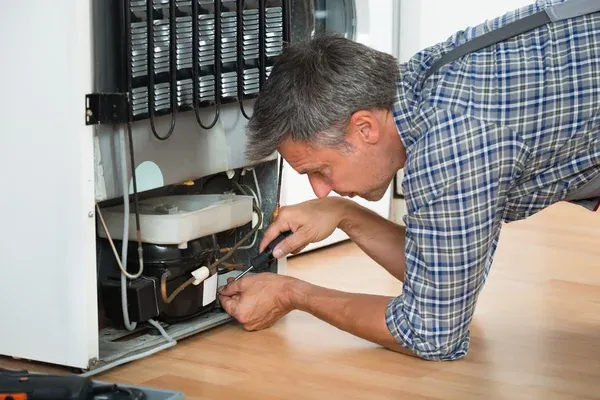 Técnico realizando conserto de geladeira